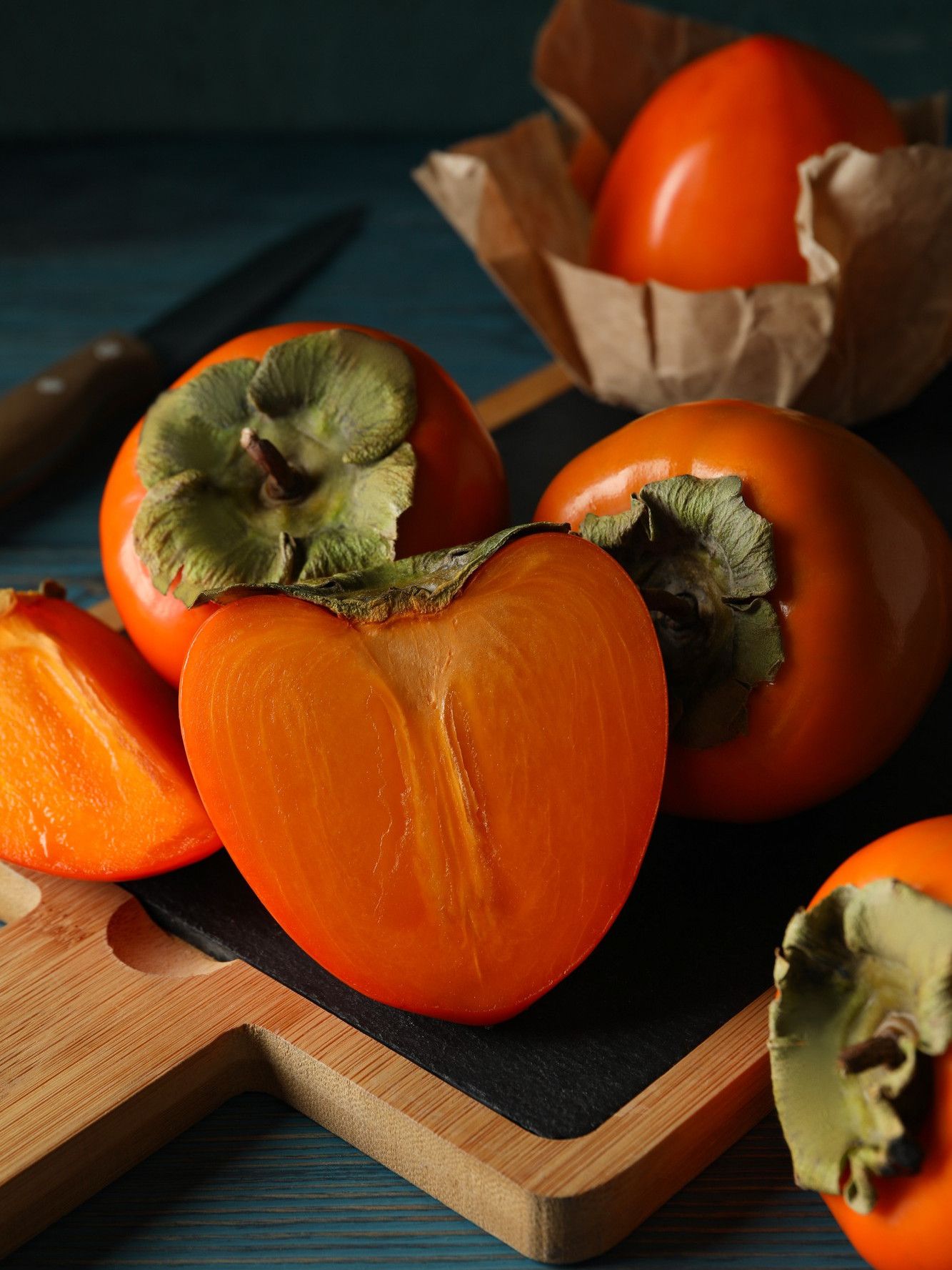 Whole and halved persimmons on a serving board