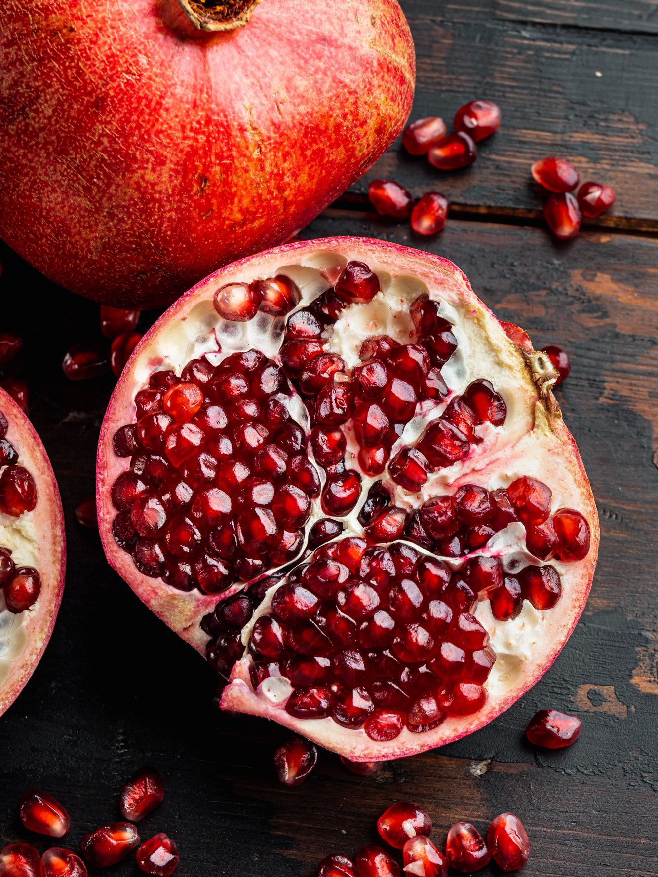 Halved pomegranate with ruby arils on a wooden table