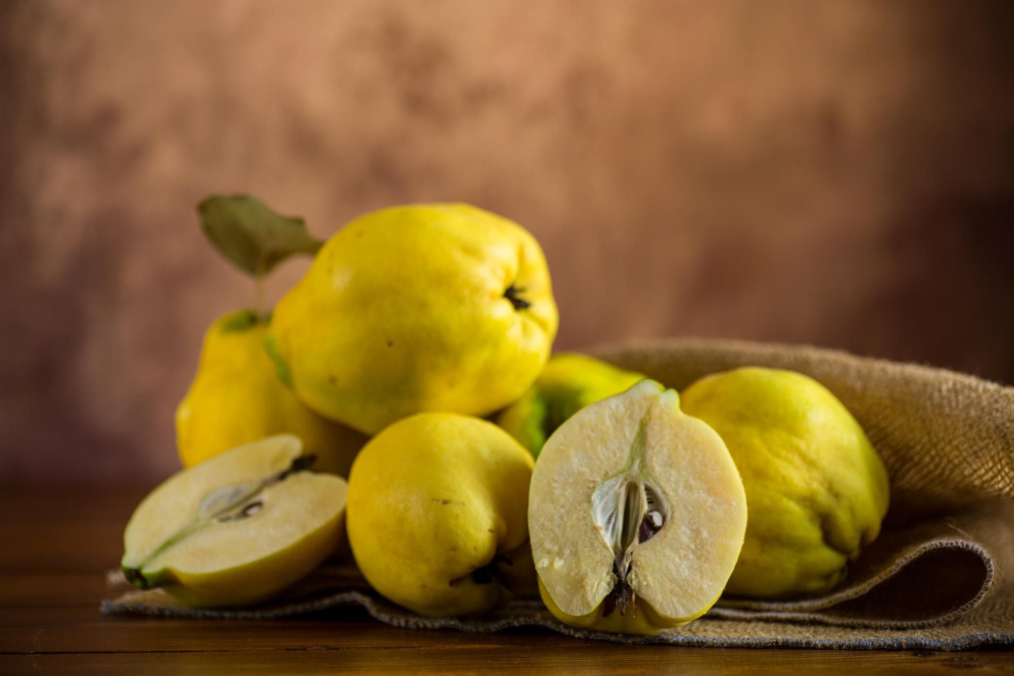 Whole and halved quinces on burlap